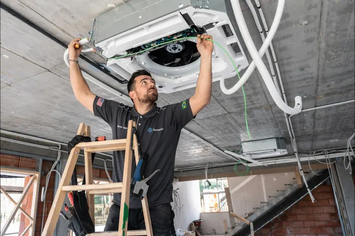 Técnico da Termaxis instalando ar-condicionado cassete no teto
